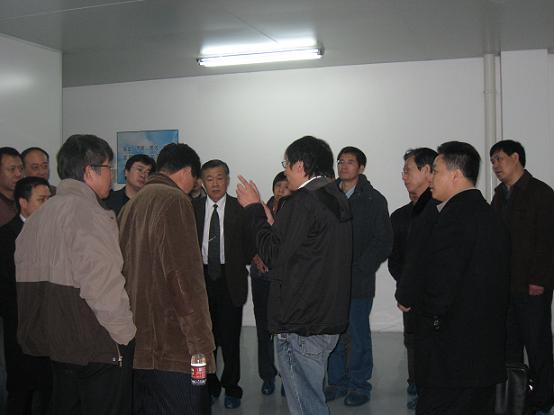 车间里，向电焊机协会参会代表讲解尊龙凯时半导体整体运行情况